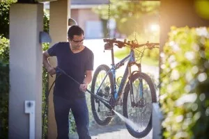 hombre limpiando bicicleta con hidrolimpiadora