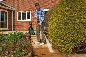 hombre limpiando el suelo del jardin con hidrolimpiadora