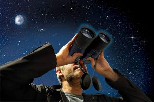 hombre mirando el cielo de noche con prismaticos