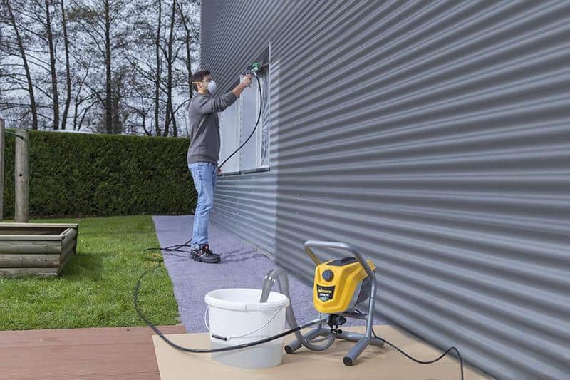 hombre pintando paredes en exteriores con pistola airless