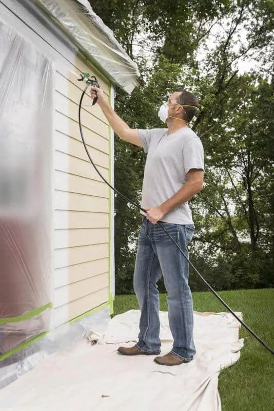 hombre usando pistola para pintar una pared